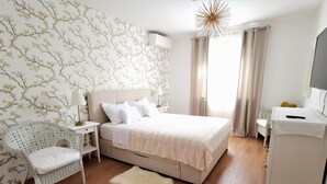 Un dormitorio con cama, una silla, un escritorio y un ventanal con cortinas.