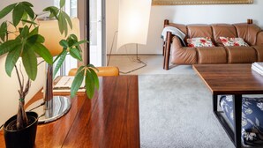 Un salon moderne avec une table basse en bois, un canapé en cuir marron, un grand miroir et une plante en pot.