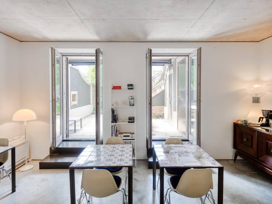A modern room with two tables and chairs, a bookshelf, and a cabinet.