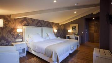 A modern hotel room with a large bed, two bedside tables, a nightstand, and a small seating area.