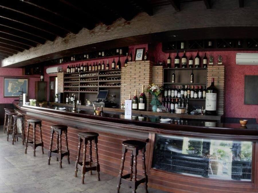 Eine Bar mit Ziegelwand, Holzstühlen und einem Weinregal.