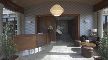 A lobby with a reception desk, seating area, and a staircase leading to another floor.