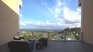 Terraza en la azotea con mobiliario exterior y vistas a un pueblo y colinas.