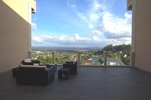 Terraza en la azotea con mobiliario exterior y vistas a un pueblo y colinas.