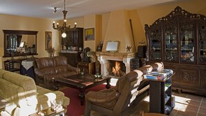 A traditional living room with leather furniture, a fireplace, and a large wooden cabinet. - Casa Rural A Rega (Poio)