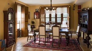 A dining room with a wooden table, four chairs, a chandelier, and a large mirror. - Casa Rural A Rega (Poio)