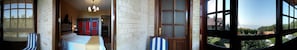 A hotel room with a large window, a bed, a chair, and a wooden door. - Casa Rural A Rega (Poio)