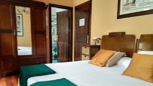 A hotel room with a large bed, two pillows, a green throw blanket, wooden furniture, and a framed picture on the wall. - Casa Rural A Rega (Poio)