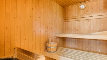 Una sauna de madera con un banco, un balde y un calentador.