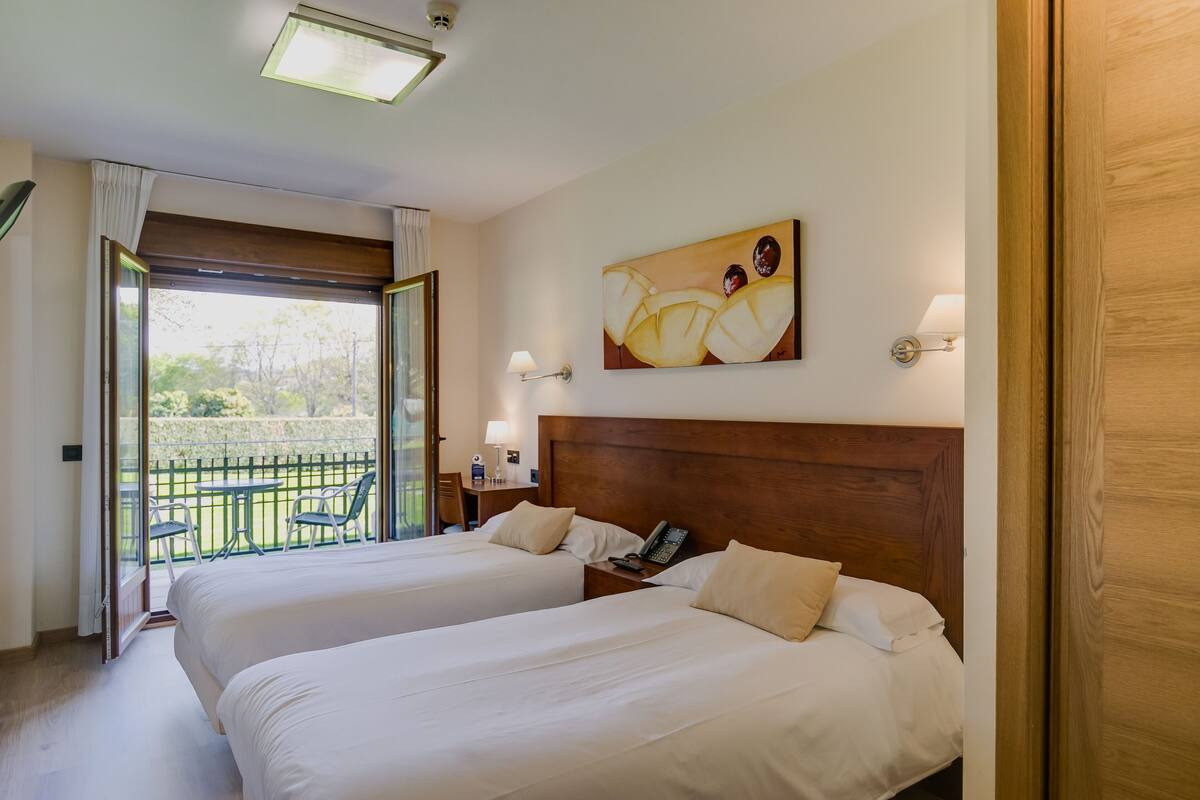 Ein Hotelzimmer mit zwei Betten, einem Balkon, einem Gemälde und einem Telefon.