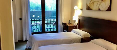 Habitación de hotel con dos camas, un balcón, un cuadro y una lámpara.