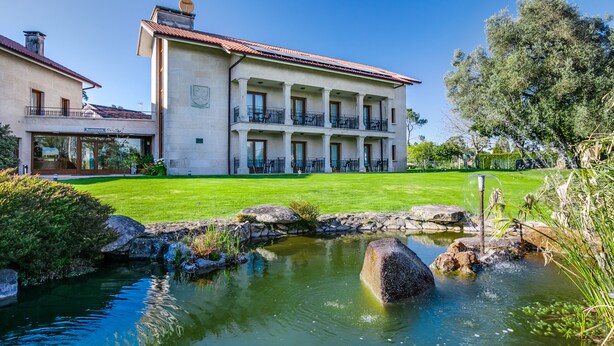 A large, two-story building with a courtyard, a small pond, and a well-maintained lawn. - Hotel Rural Campaniola (Pontevedra)