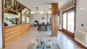 A modern interior with a wooden staircase, a dining area, and a large window with a view. - Hotel Rural Campaniola (Pontevedra)