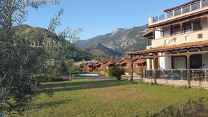Un hotel con varias cabañas de madera, una piscina y montañas al fondo.