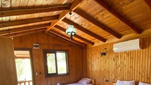 Una cabaña de madera con dos camas, un ventilador de techo y una ventana.
