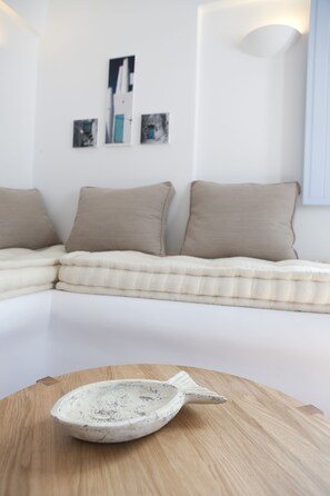 Un salon moderne avec un canapé d’angle, une table ronde en bois sur laquelle repose un bol en céramique, et des œuvres d’art accrochées au mur.