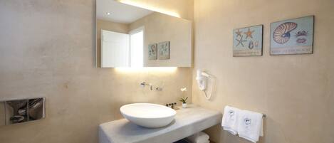 A modern bathroom with a large mirror, a white sink, and two wall-mounted artworks depicting sea creatures.