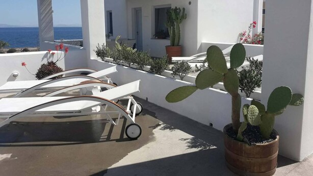 A white building with a patio area, a carport, and a view of the sea. - Sun Anemos Resort (Santorini)