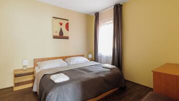 A neatly made bed with a wooden headboard, a bedside table with a lamp, and a wall-mounted artwork.