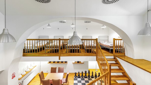 A modern loft-style bedroom with a loft bed, a dining area with a chessboard, and a staircase. - Hotel Stary Pivovar (Prague)