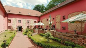 A courtyard with a brick pathway leading to a building with stone walls and a red facade. - Hotel Stary Pivovar (Prague)