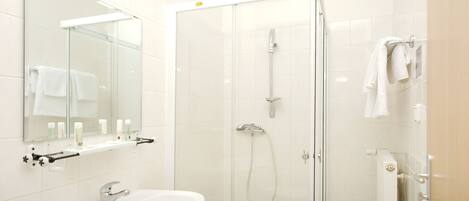 A modern bathroom with a glass-enclosed shower, a white sink, and a mirror above the sink.
