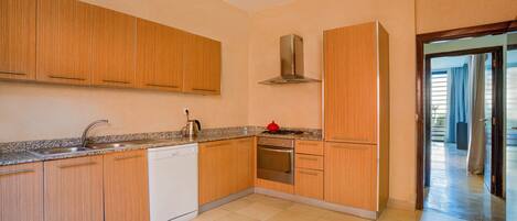 A kitchen with wooden cabinets, a stainless steel range hood, a dishwasher, and a stove.