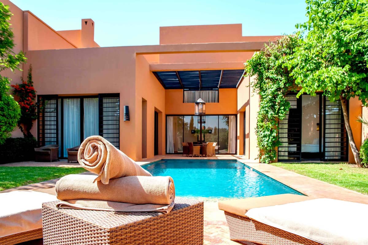 A modern house with a swimming pool, outdoor seating, and a covered patio area.