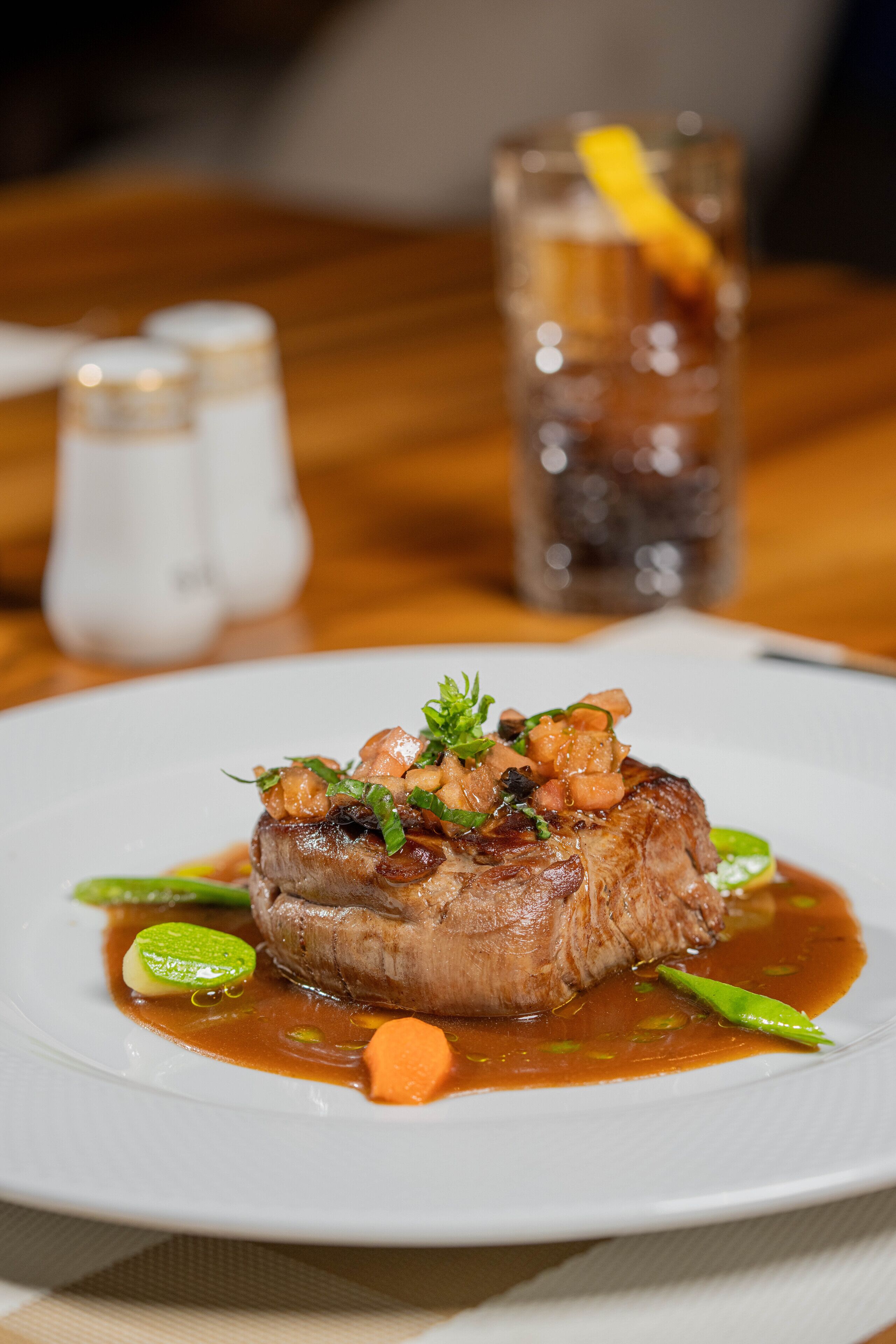 A plate of food with a steak, vegetables, and sauce.