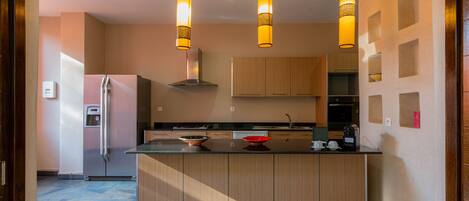 Een moderne keuken met houten kastjes, een centraal eiland en hanglampen.