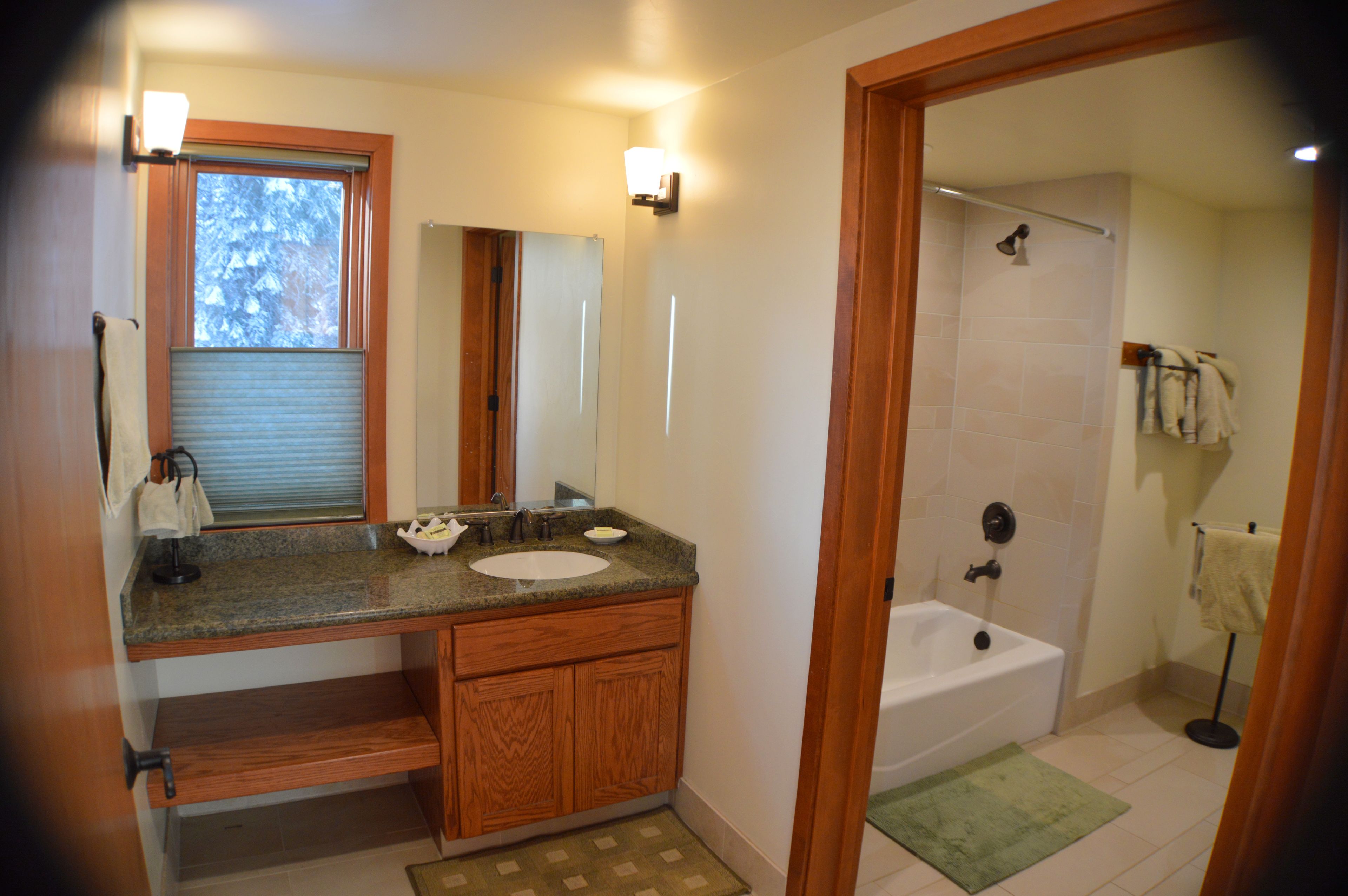 A bathroom with a sink, mirror, and bathtub.