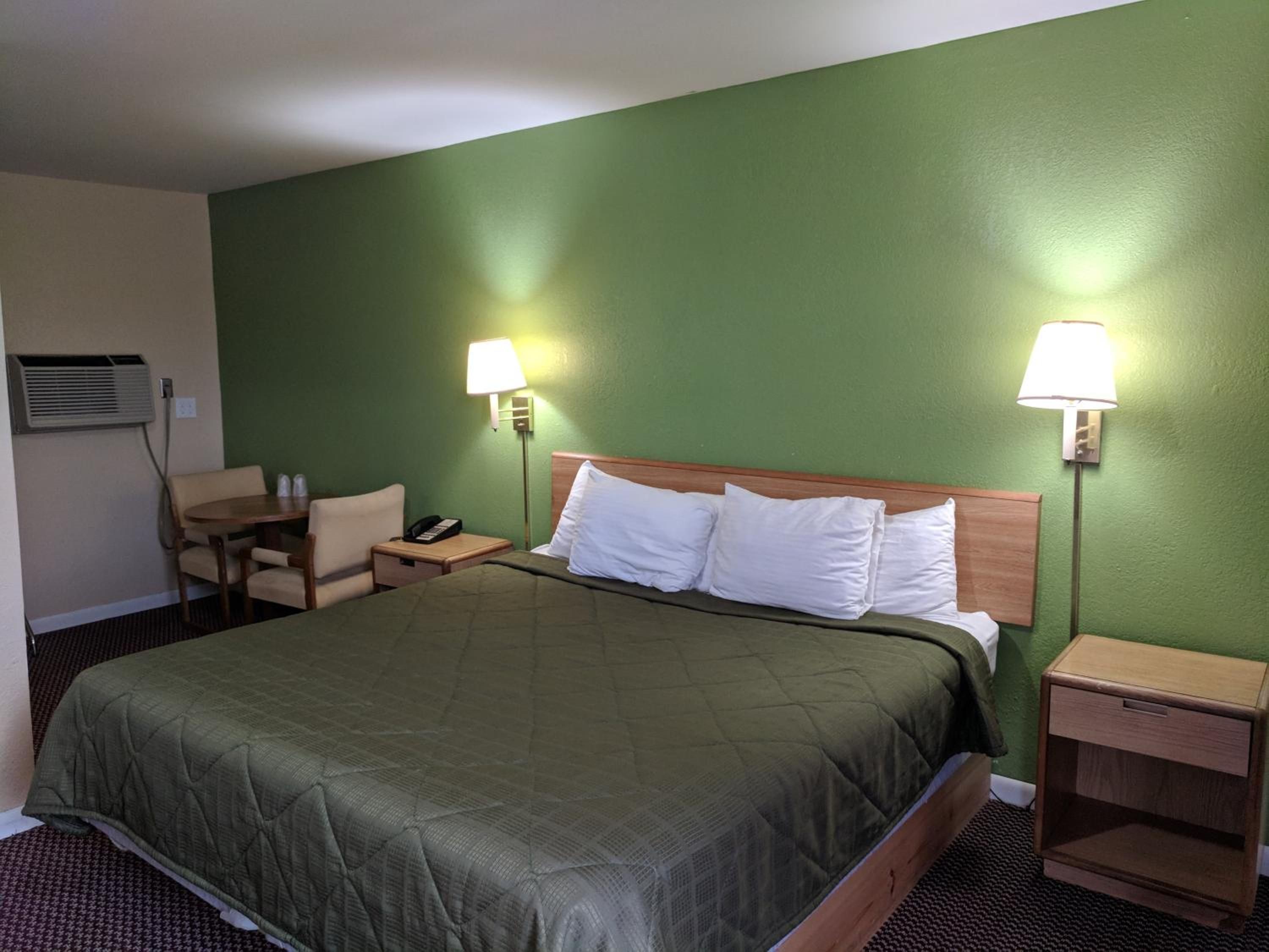 A hotel room with a large bed, two bedside tables, a chair, and a desk.