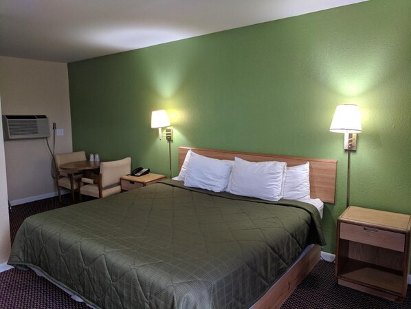 Habitación de hotel con una cama grande, dos mesitas de noche, una silla y un escritorio.