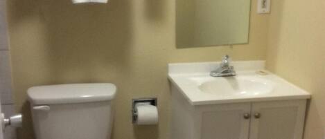 Un bagno con il water, un lavandino, uno specchio e un cestino.