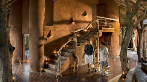 Ein rustikales Interieur mit einer Holztreppe, Steinpfeilern und Laternen.