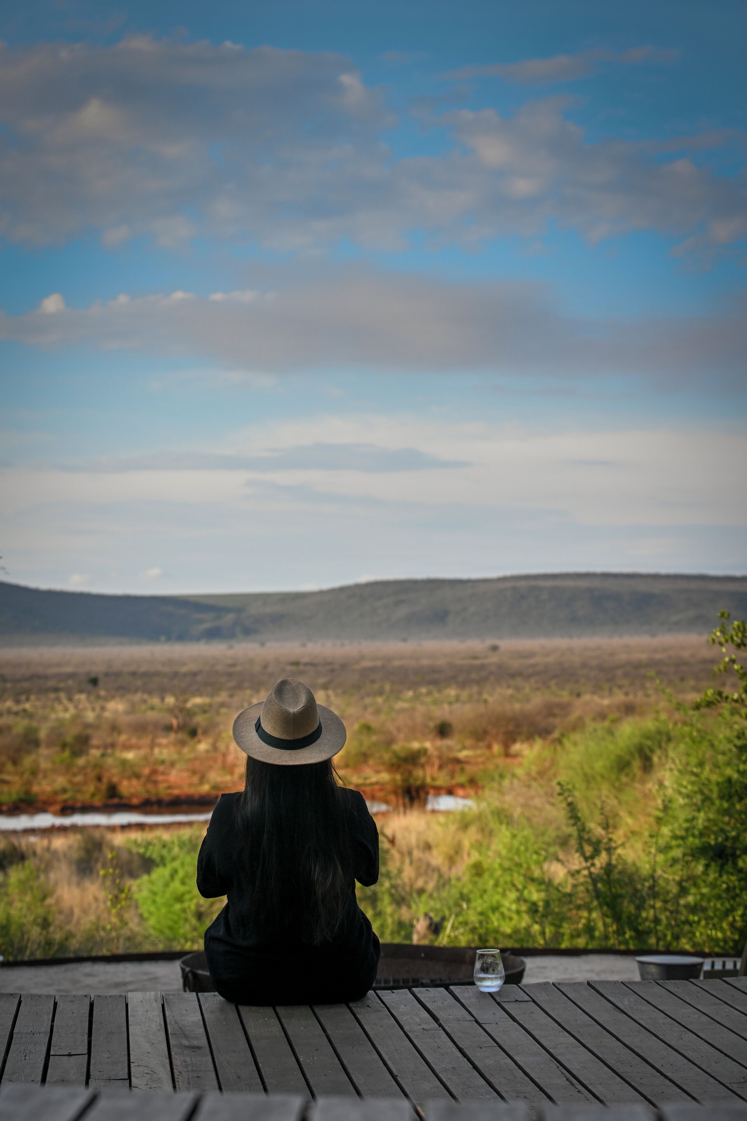 A person sitting on a wooden deck with a view of a natural landscape.