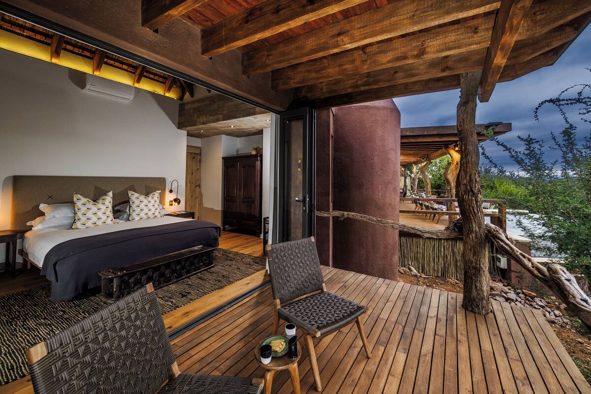 Ein Schlafzimmer mit einem großen Bett, einer Holzbalkendecke und Blick auf eine Terrasse.