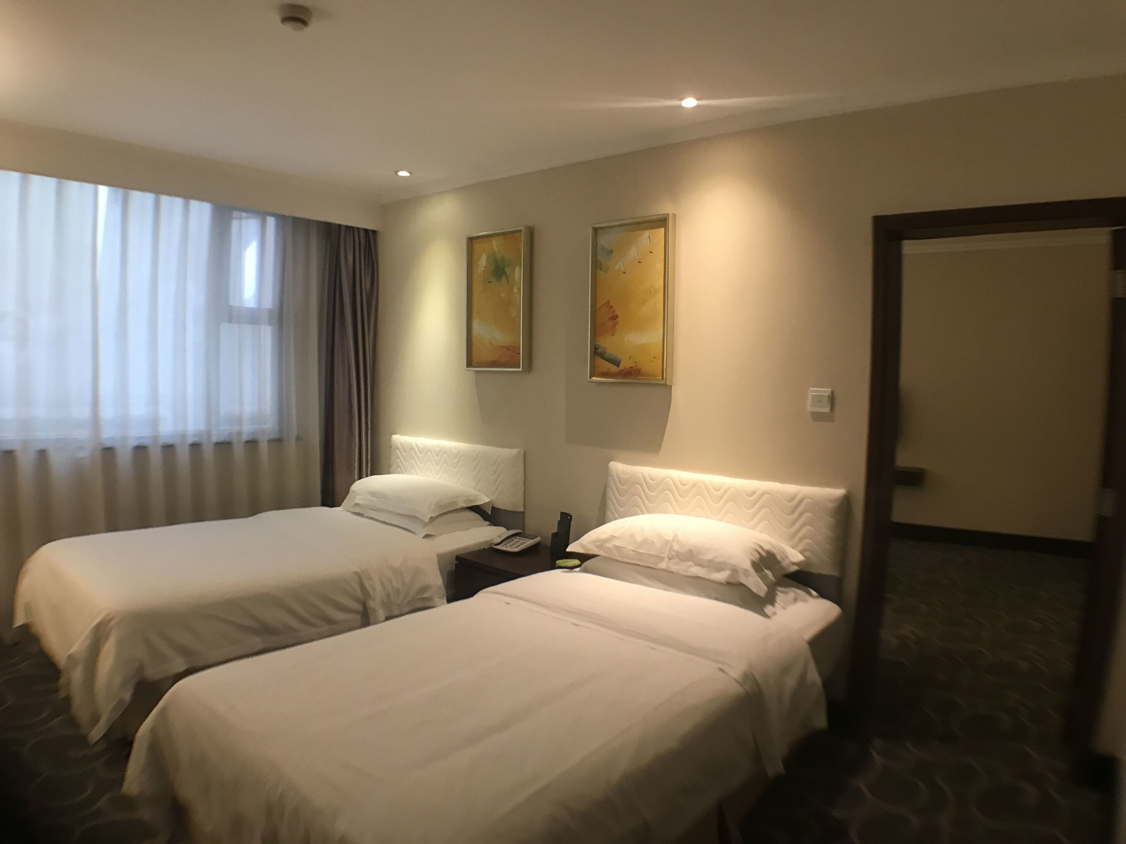 Ein Hotelzimmer mit zwei Betten, einem Nachttisch, einem Telefon und einem Bild an der Wand.