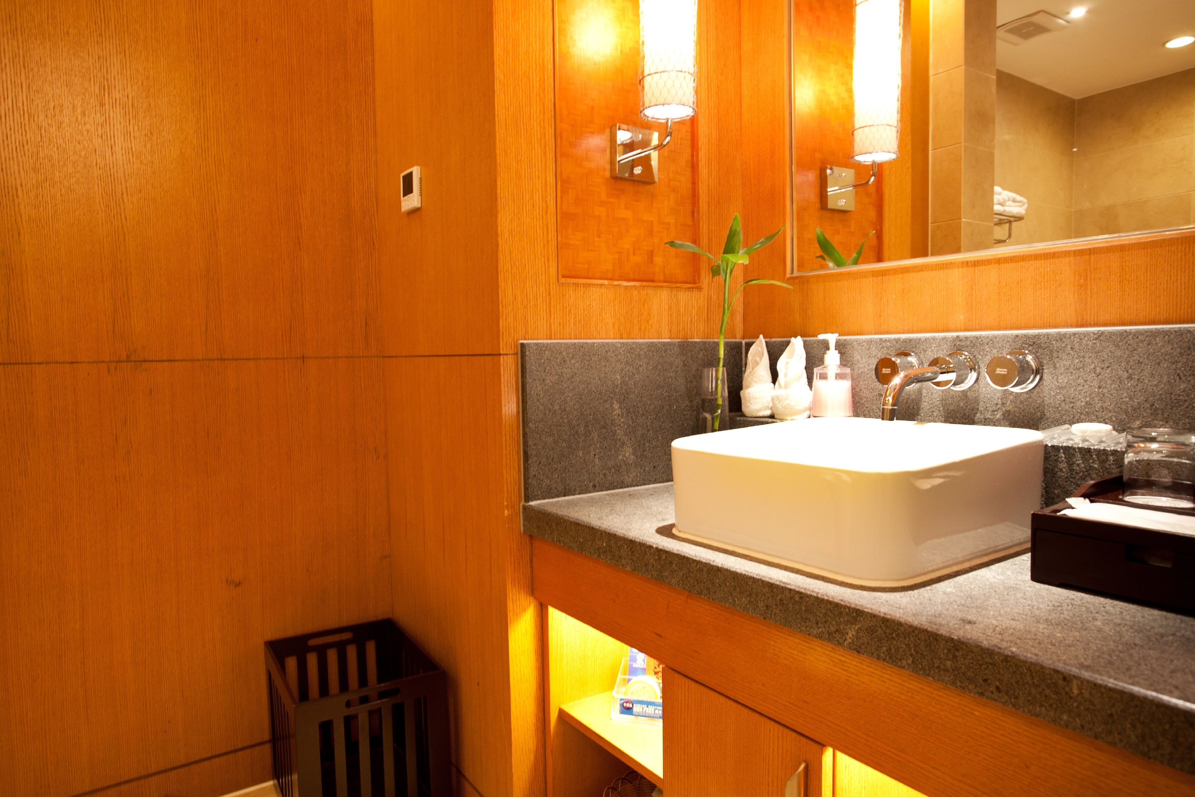 Un baño con tocador de madera, un lavabo blanco y un espejo encima.