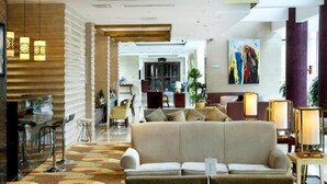 A modern hotel lobby with a sofa, lamps, and a painting. - Garden Hotel (Suzhou)