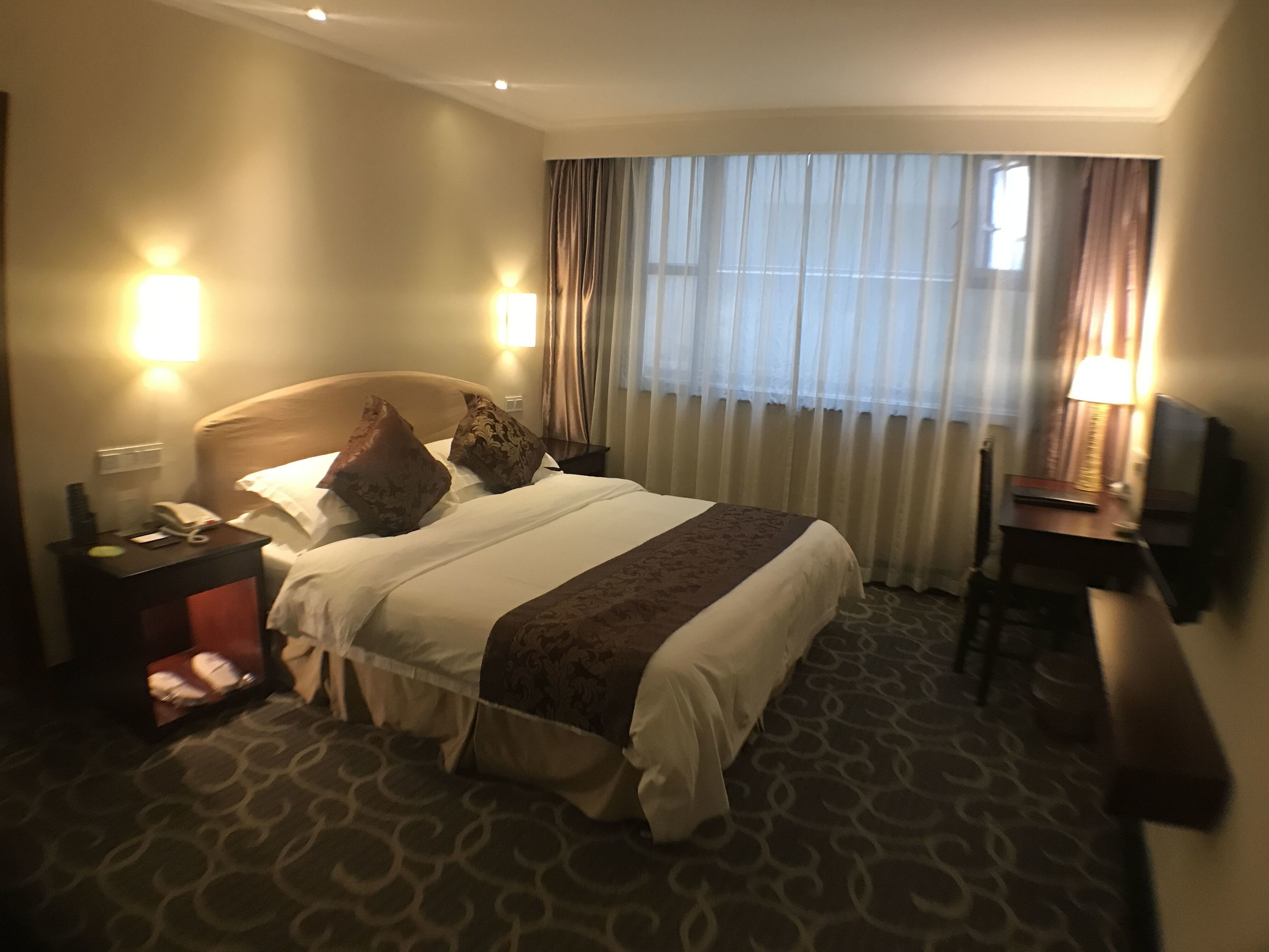 Une chambre d’hôtel équipée d’un lit, de lampes de chevet, d’un bureau et d’une télévision.