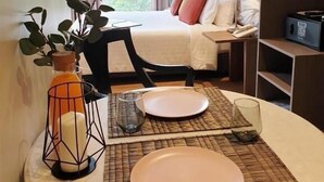 Habitación de hotel con cama, mesita de noche, lámpara y vistas a zonas verdes.