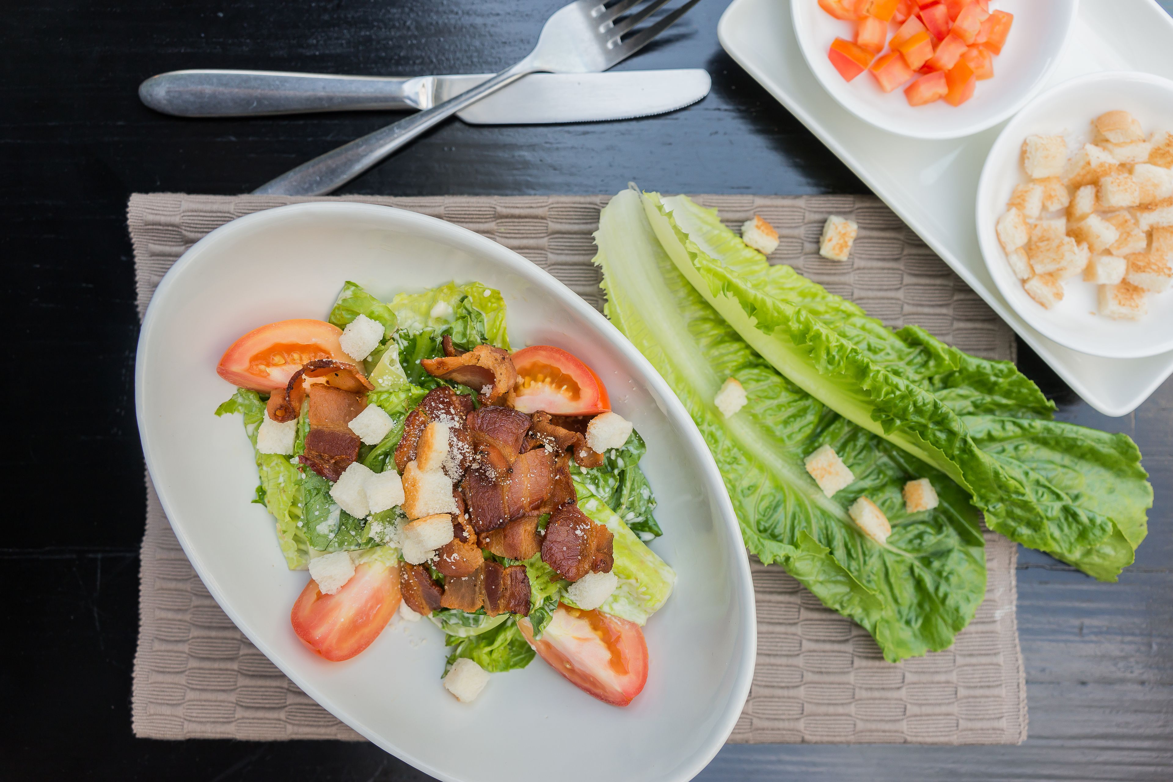 Een salade met sla, tomaten en croutons op een bord.