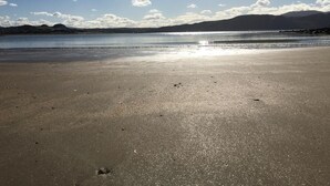 Een strand met een heldere lucht en verre bergen.