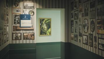 Ein Korridor mit gerahmten Fotos an den Wänden, einem Schild für die zweite Etage und einem gemusterten Boden.