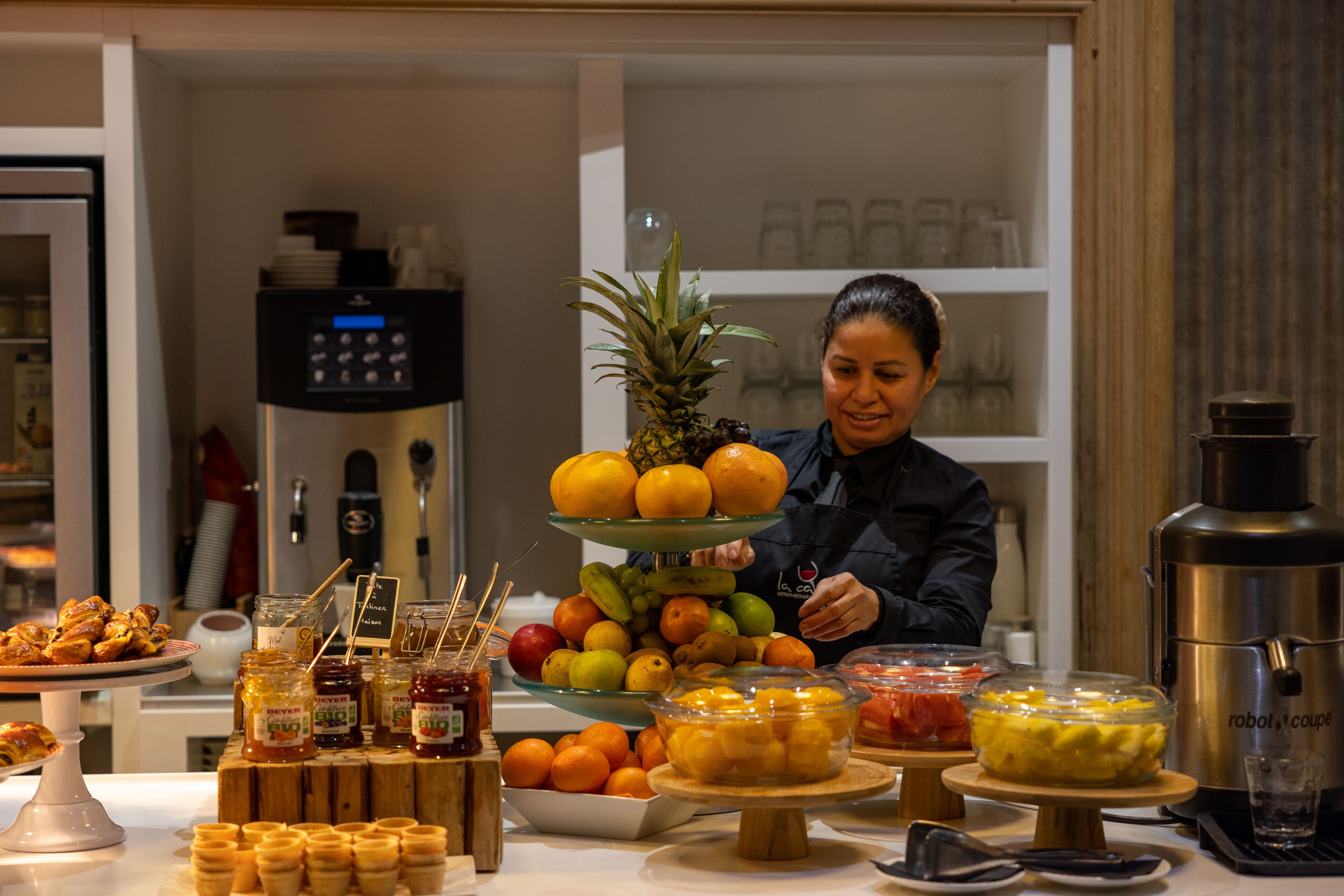 A buffet table with various food items and a person serving.
