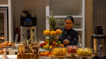 A buffet table with various food items and a person serving.