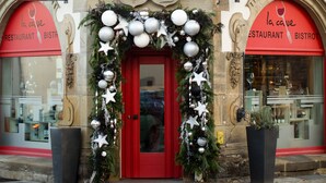 A building facade with a statue above the entrance, a red door, and Christmas decorations.