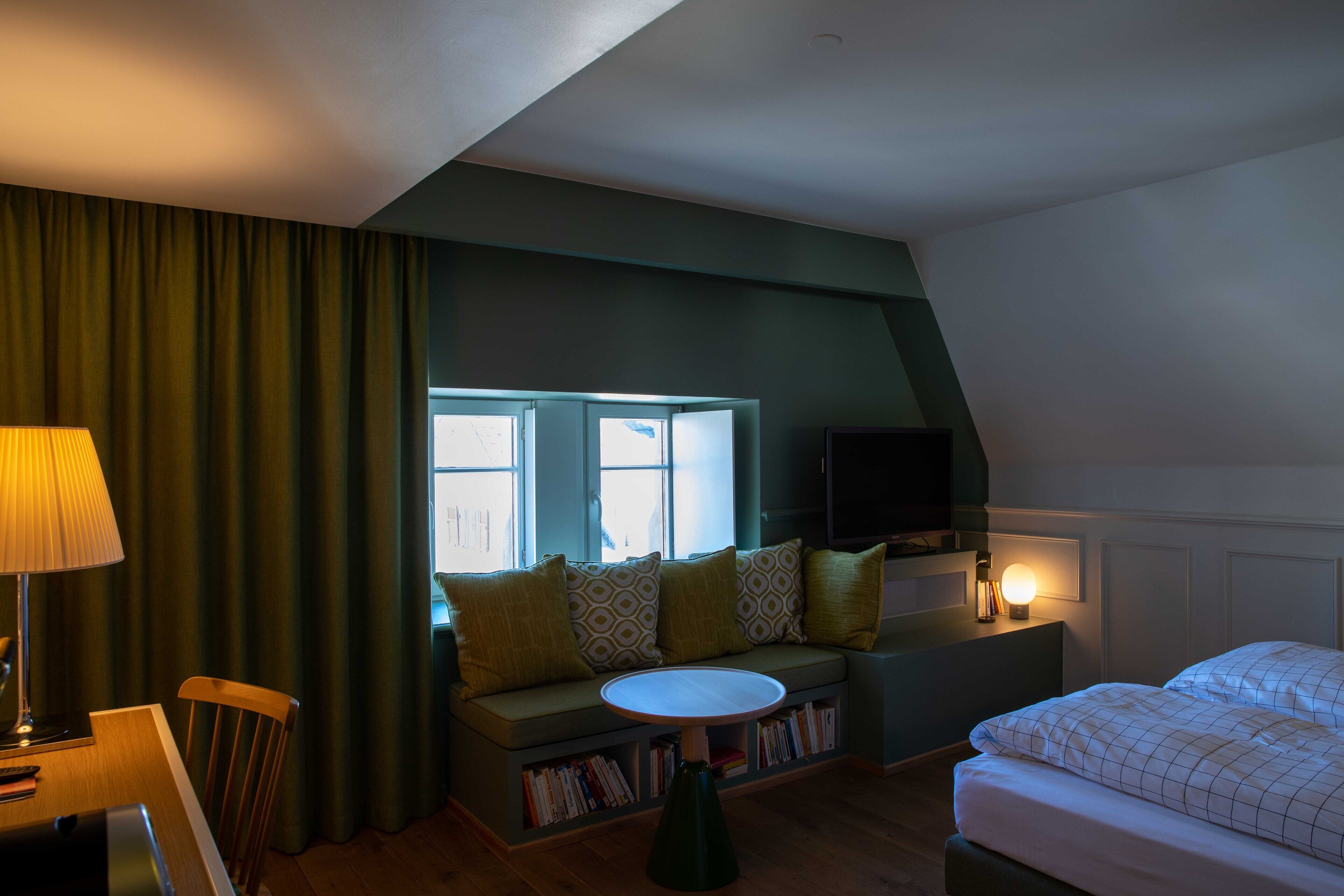 A cozy room with a sofa, a small table, a TV, and a bed.