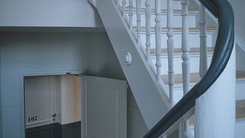 A staircase with white balusters and a dark handrail, leading to a room with a door labeled "107".